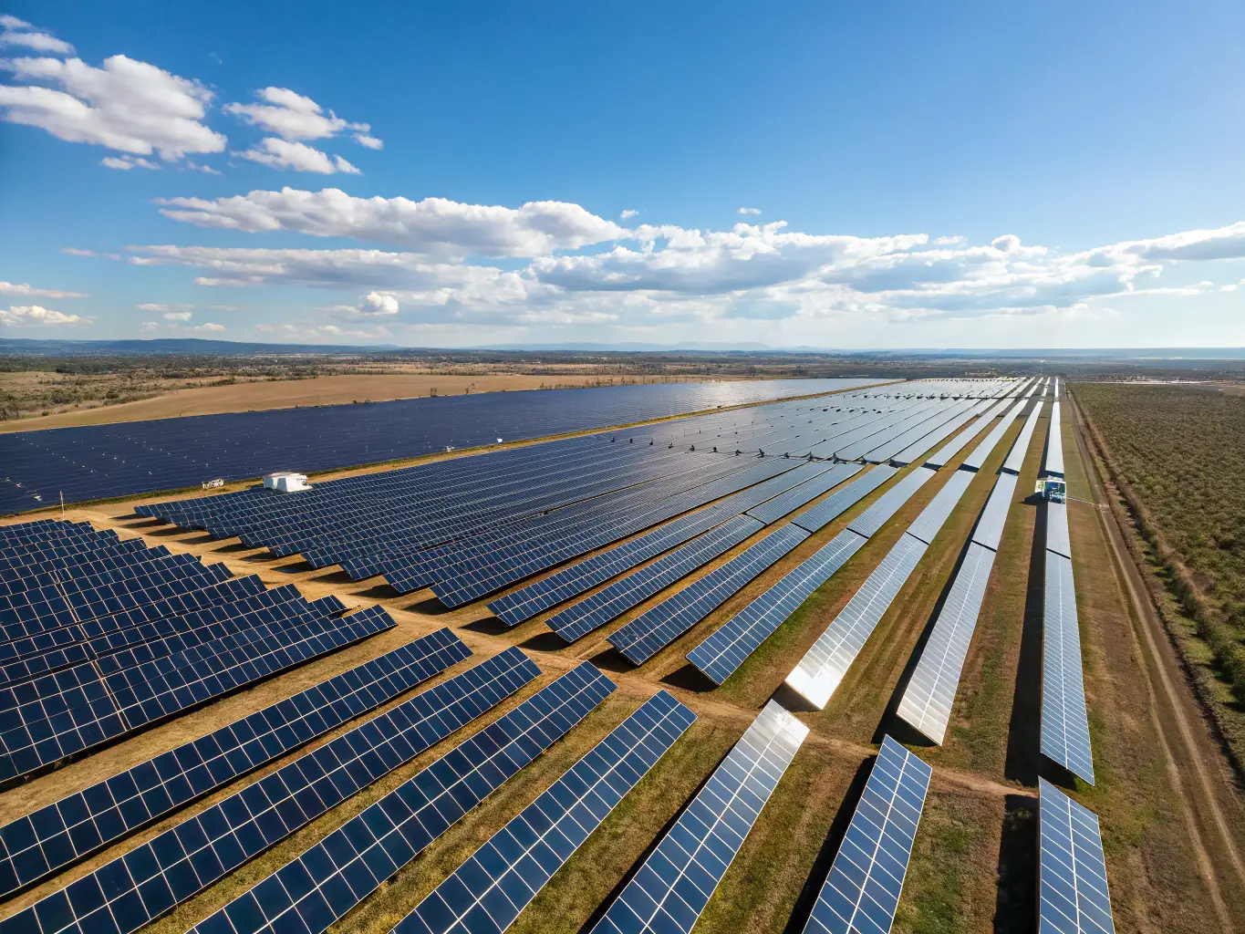 A large-scale commercial solar farm with rows of solar panels stretching into the distance under a clear blue sky, illustrating the potential for businesses to generate clean energy on a large scale.